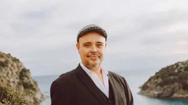 Portrait d'Aurélien Gillet, fondateur de Mana, en costume et casquette devant la mer