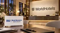 hall d’hôtel, avec le logo bleu Best Western Hotels & Resorts sur une plaque au premier plan et le logo WorldHotels sur le mur derrière la réception, évoquant la nouvelle marque globale du groupe.