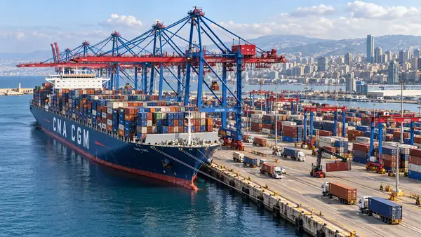 Porte-conteneurs CMA CGM amarré au terminal du port de Beyrouth au Liban, entouré de grues portuaires, de conteneurs et de véhicules logistiques, illustrant l’investissement de 100 millions de dollars du groupe français pour agrandir et moderniser l’infrastructure.