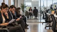 Candidats à l’emploi attendant un entretien dans un espace de recrutement à Paris face à plusieurs postes de travail vacants, illustration du paradoxe du marché de l’emploi français entre hausse du chômage et difficultés de recrutement.