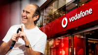 Xavier Niel, fondateur de Free, souriant, avec le logo de Vodafone en arrière-plan, symbolisant son acquisition de parts dans l'entreprise.